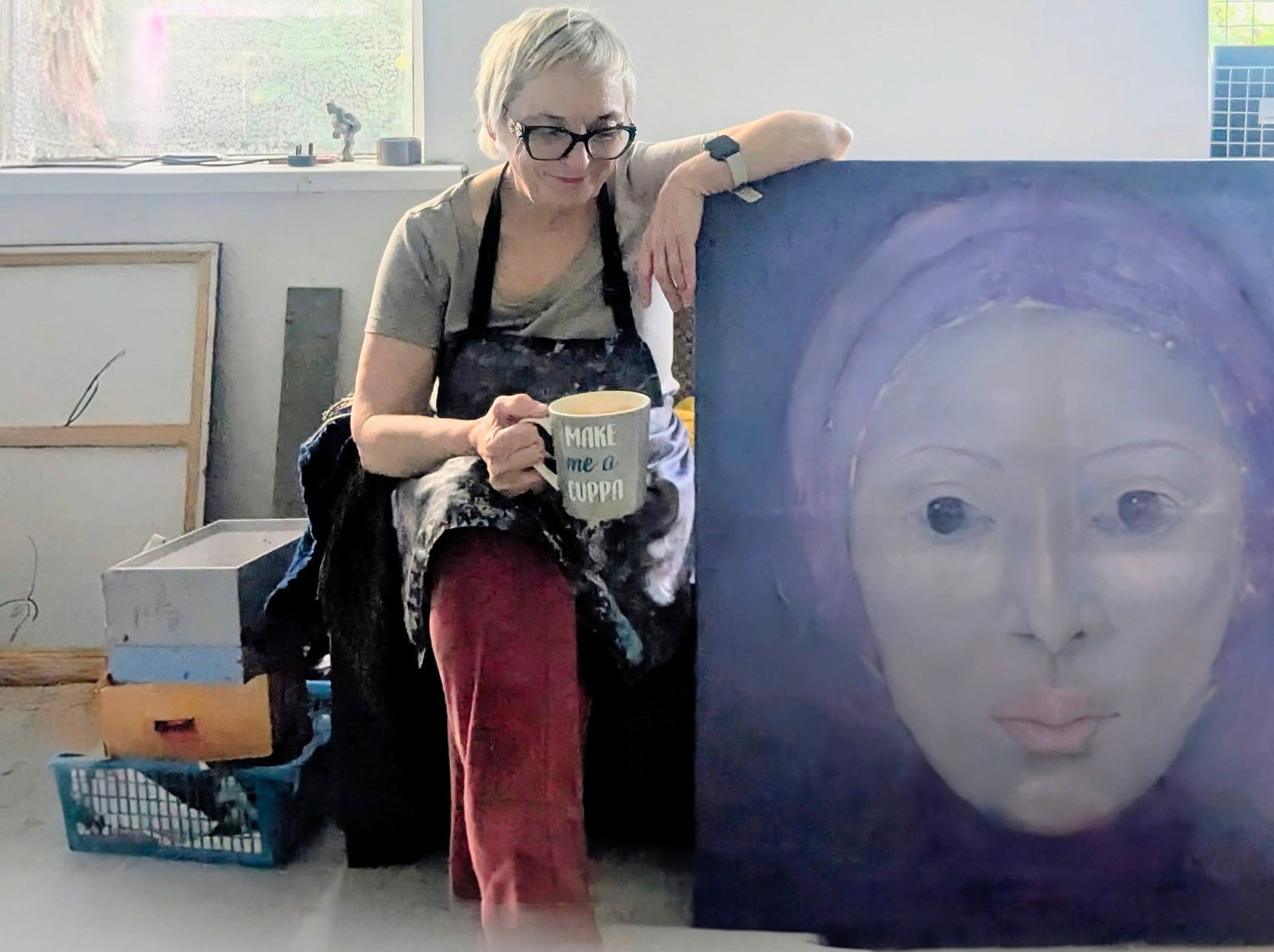 Ann Mitchell in her art studio holding one of her oil portraits